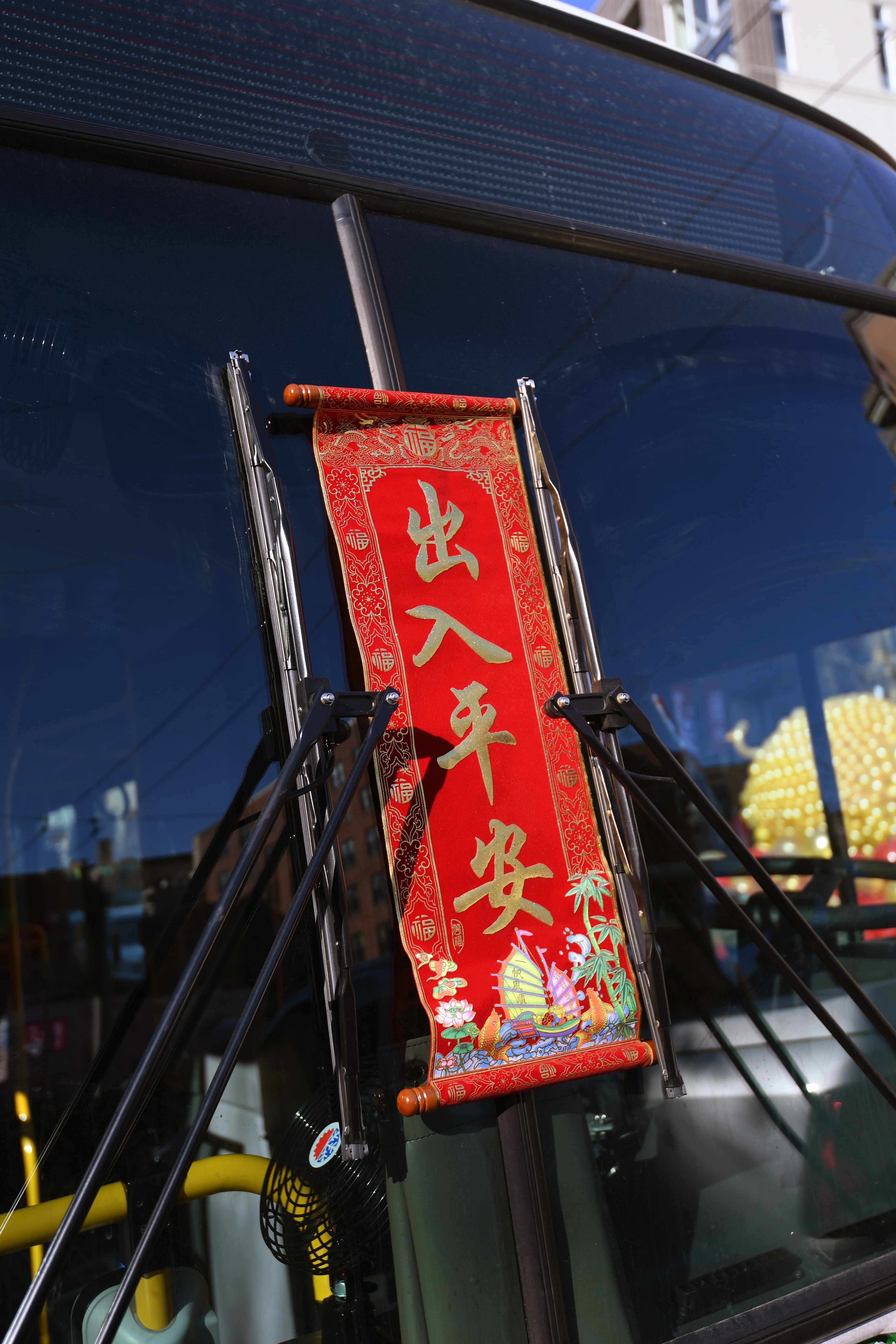 A red Lunar New Years banner on the windshield of a bus
