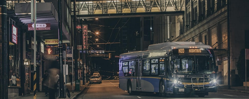 A NightBus departing from a bus stop on an empty street