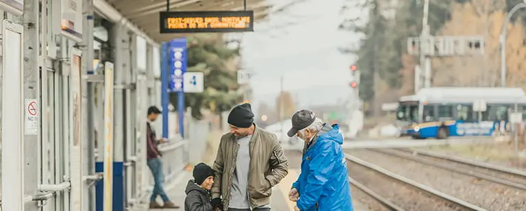 A family waiting for a West Coast Express train to arrive at the station platform