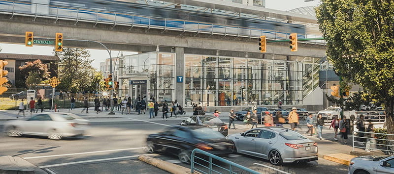 Cars driving out of an underground parkade with a SkyTrain running in the background