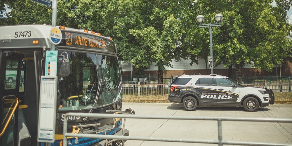 A transit police car parked behind a bus at a transit exchange