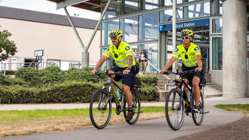 Two Transit Security Officers on bicycles outside Braid SkyTrain Station