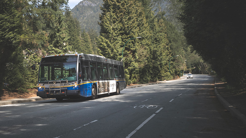A TransLink bus cruising along a scenic green highway