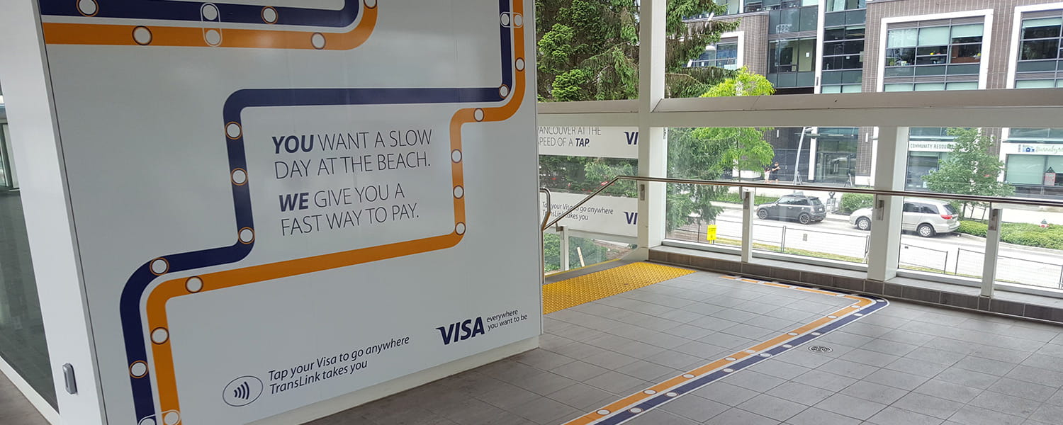 A SkyTrain station with Visa Tap to Pay advertising plastered all over the walls