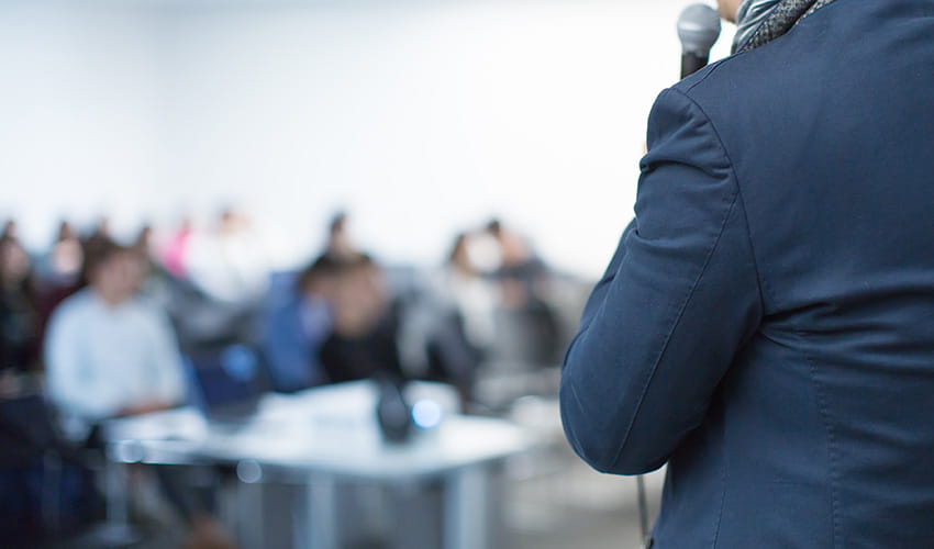 A person in a suit giving a presentation to a group of people in a board room