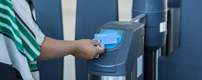 A person tapping their Compass card to open the fare gate