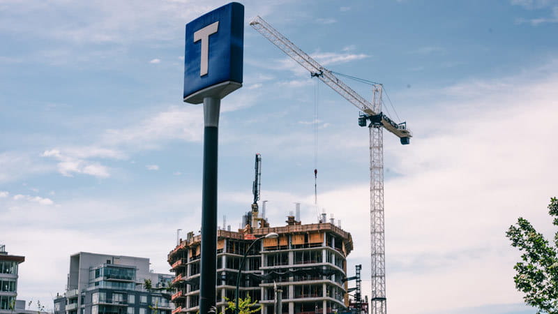 TransLink T logo signage with a crane and real estate development in background