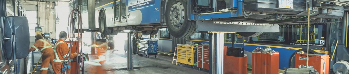 Mechanics at a depot working underneath an elevated bus