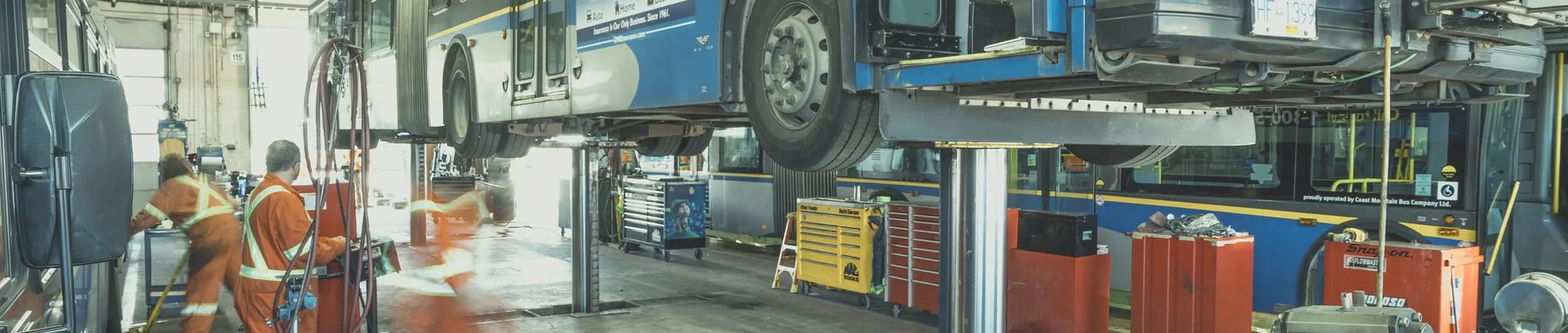 Mechanics at a depot working underneath an elevated bus