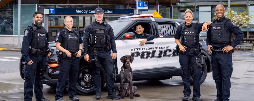 Transit police officers standing by the police car in front of Moody Centre Station