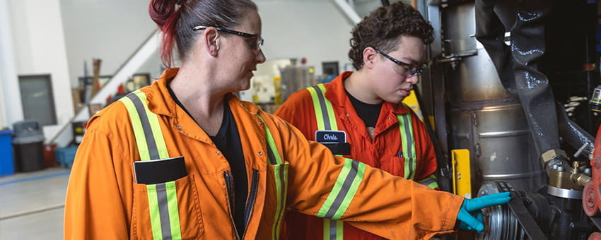 Two mechanics  looking under the hood of a bus