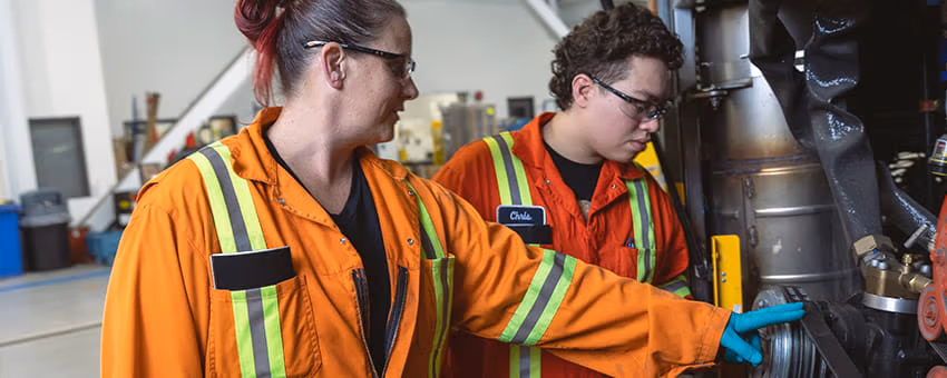Two mechanics looking under the hood of a bus