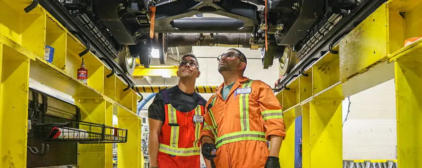 Two TransLink employees looking under a SkyTrain