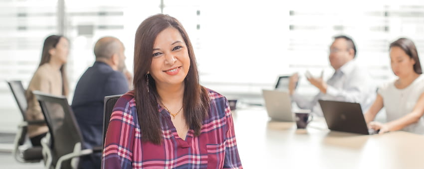 A portrait of a TransLink office employee in a meeting room with people in background