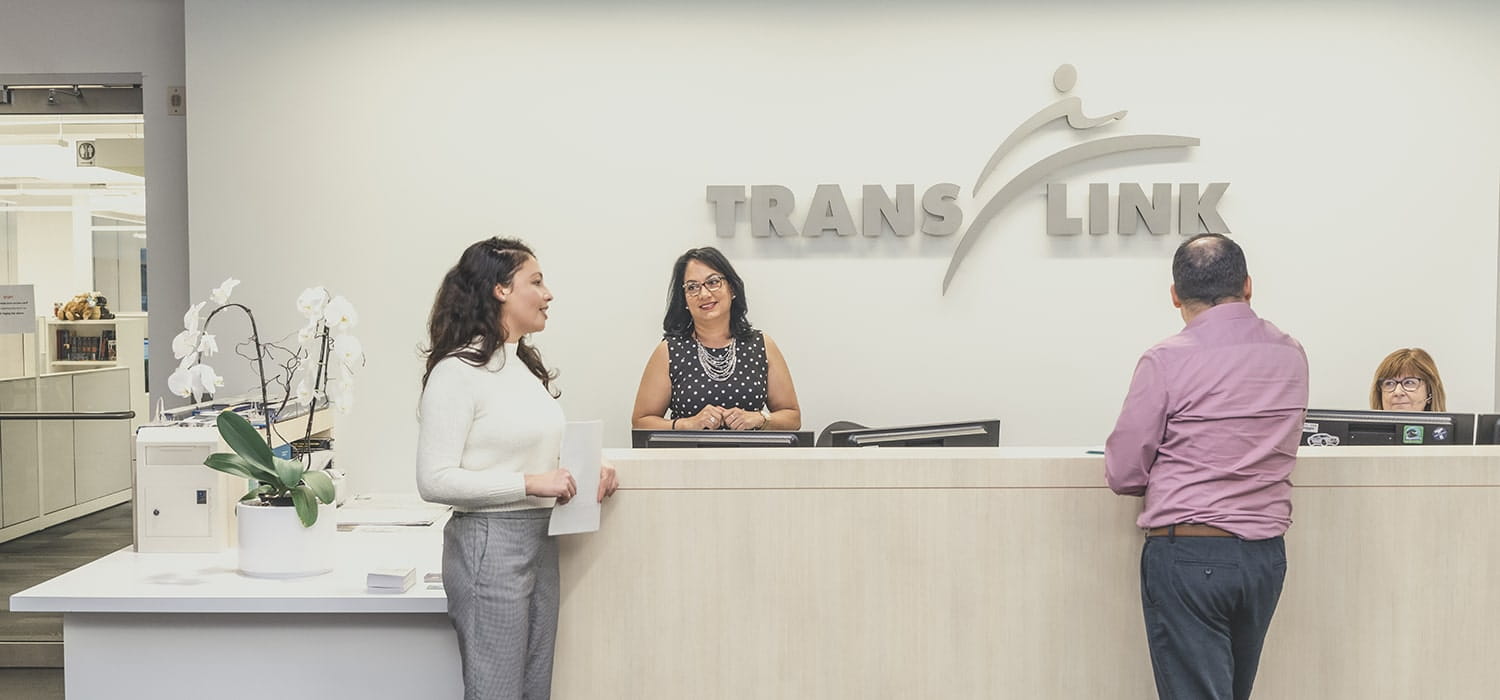 A receptionist helping out two people inside TransLink head office