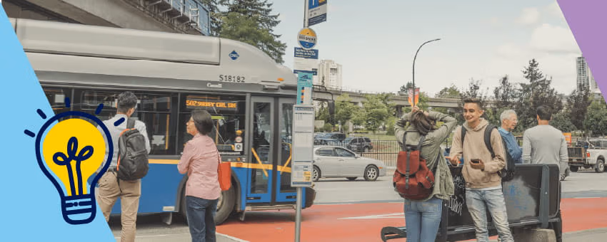 People waiting at a bus stop as a TransLink bus pulls in, with a SkyTrain guideway in the background