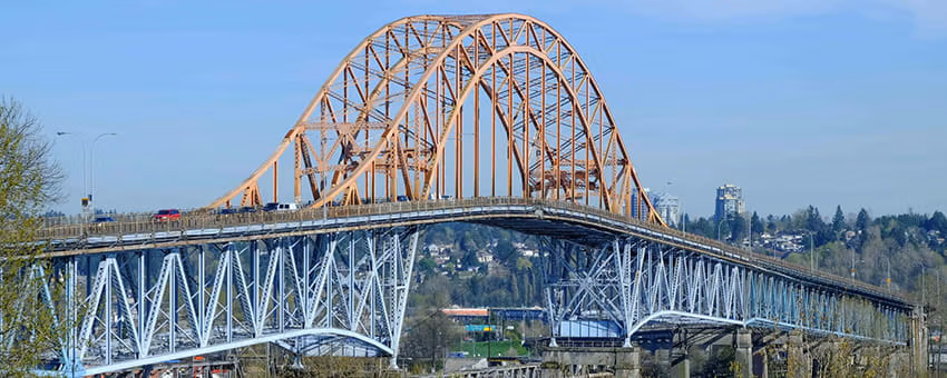 Pattullo Bridge with orange steel arches and blue truss spans over the Fraser River.