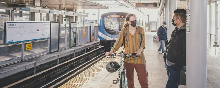 Passengers chat on the SkyTrain platform as a SkyTrain approaches