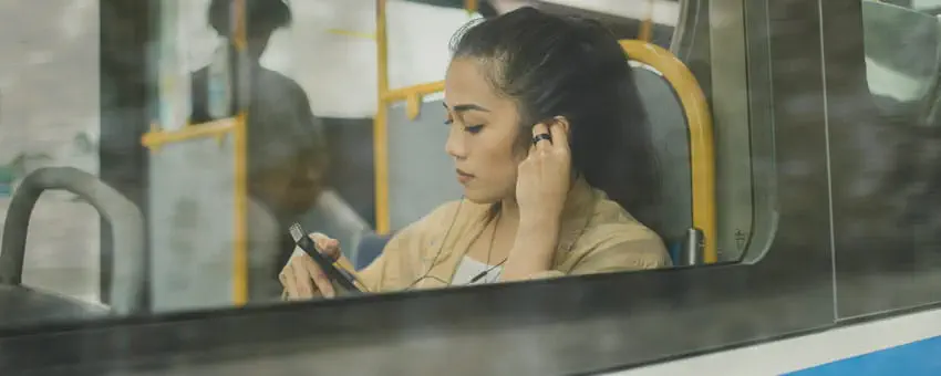 woman on RapidBus and using mobile device with headphones