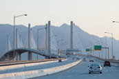 Cars driving across a bridge with mountains in the background