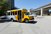 A HandyDart van driving near a SkyTrain station