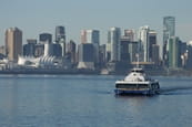A SeaBus sailing across Burrard Inlet with downtown Vancouver in the background