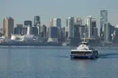 A SeaBus sailing across Burrard Inlet with downtown Vancouver in the background