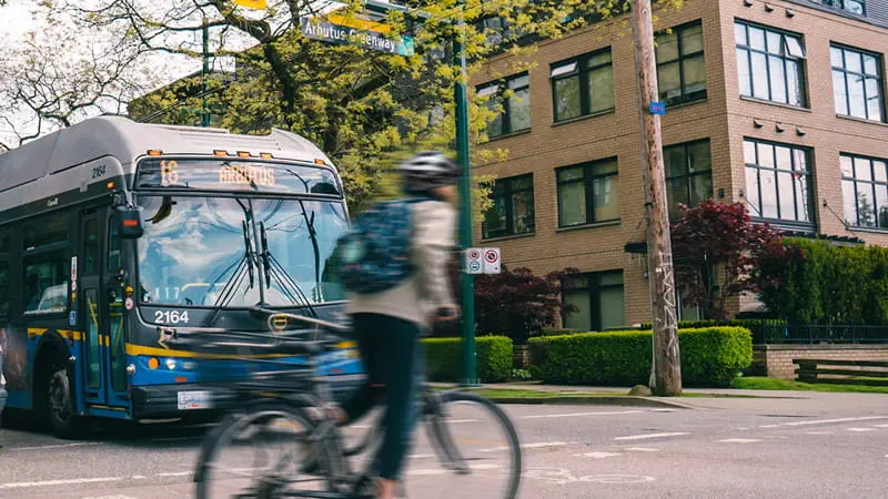 Cyclist riding by a bus on Arbutus street