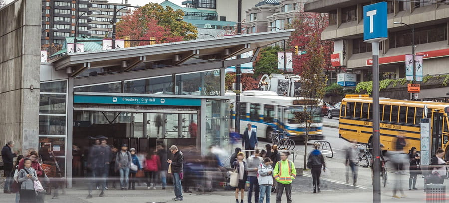 People lining up for a bus infront of a Canada Line station