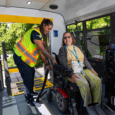 Driver securing a wheelchair inside a HandyDART