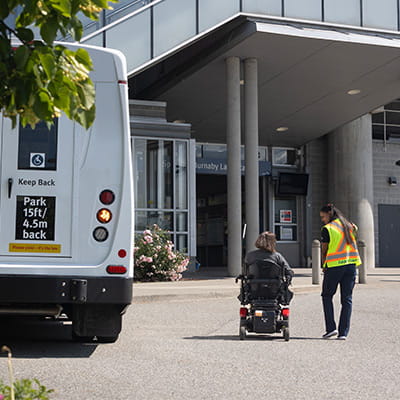 HandyDART driver assisting a passenger arriving at SkyTrain station