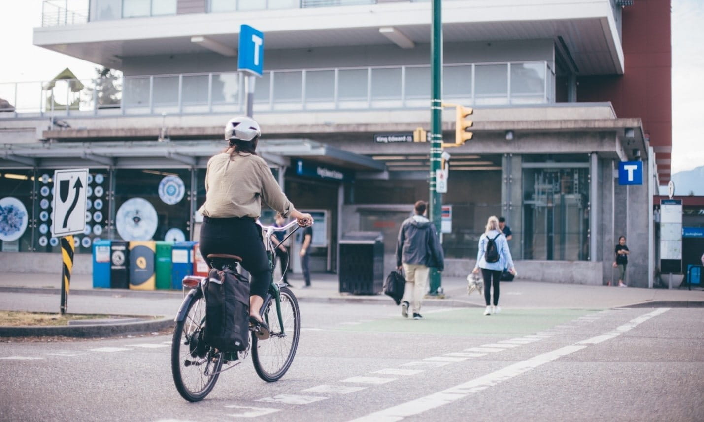 A woman biking towards a SkyTrain station