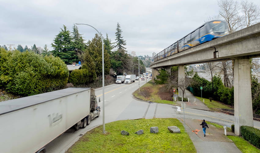 A truck drives along Stewardson Way as the SkyTrain cruises on the overpass above