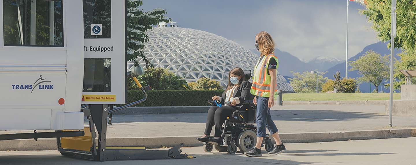 A HandyDART attendant assisting a woman in a wheelchair