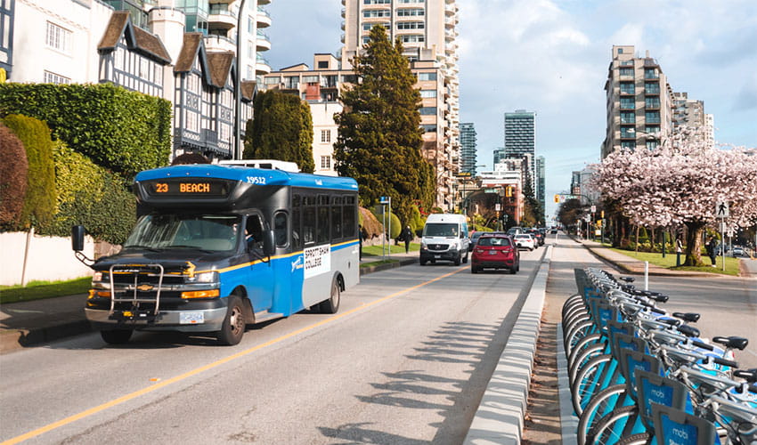 People walking around a bus exchange with the 321 parked next to a bus stop in the distance
