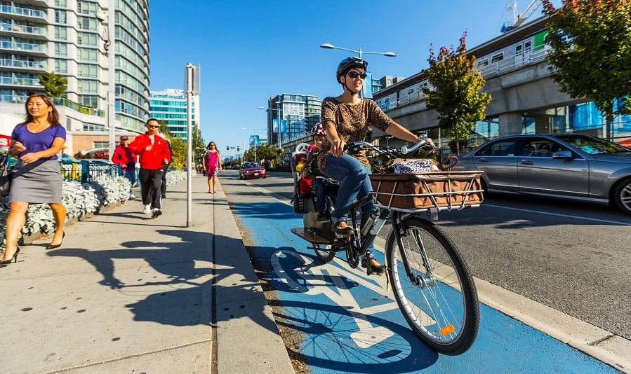 A woman riding her bike down a blue bike lane on the street