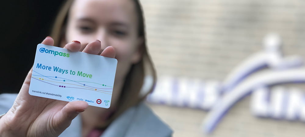 A woman holding up a new mobility themed compass card