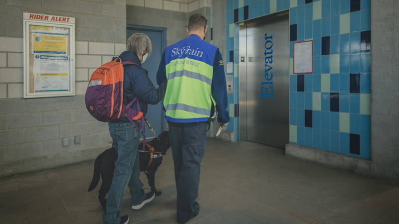 SkyTrain Station Attendant assisting senior customer to the elevator
