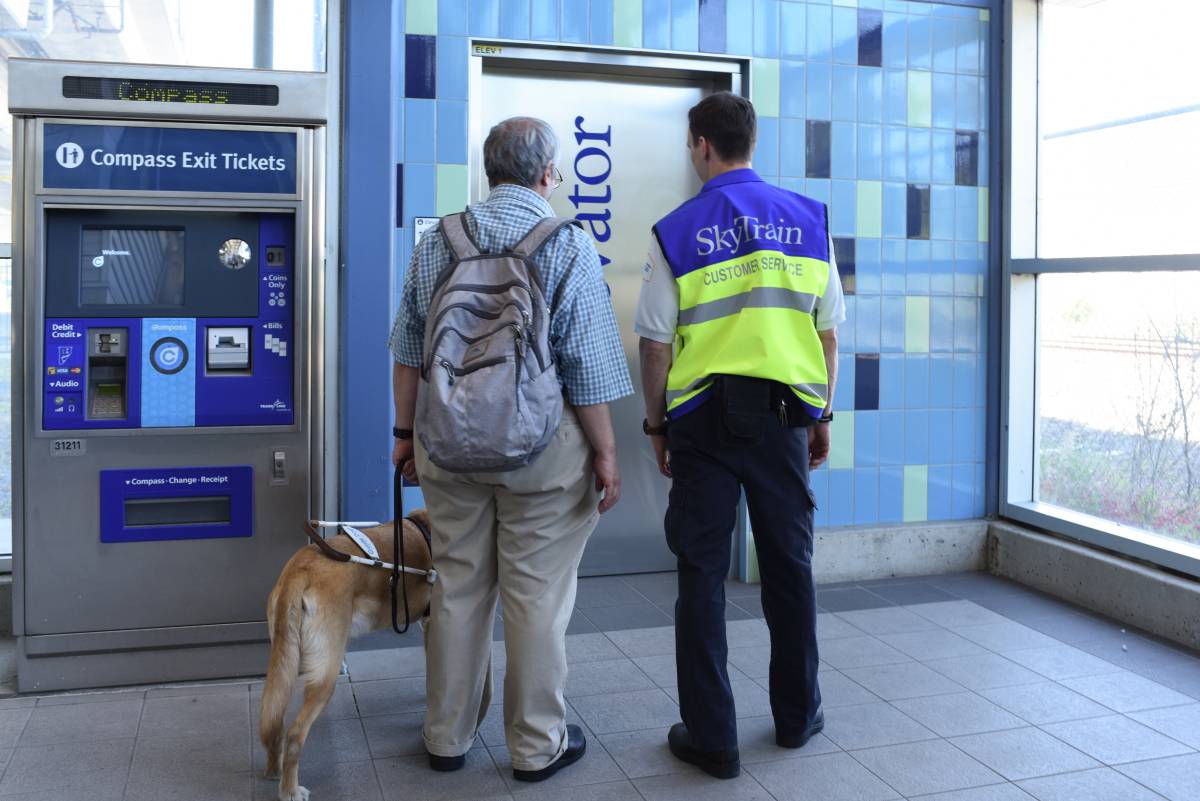SkyTrain attendant helping a passenger with a guide dog find the elevator