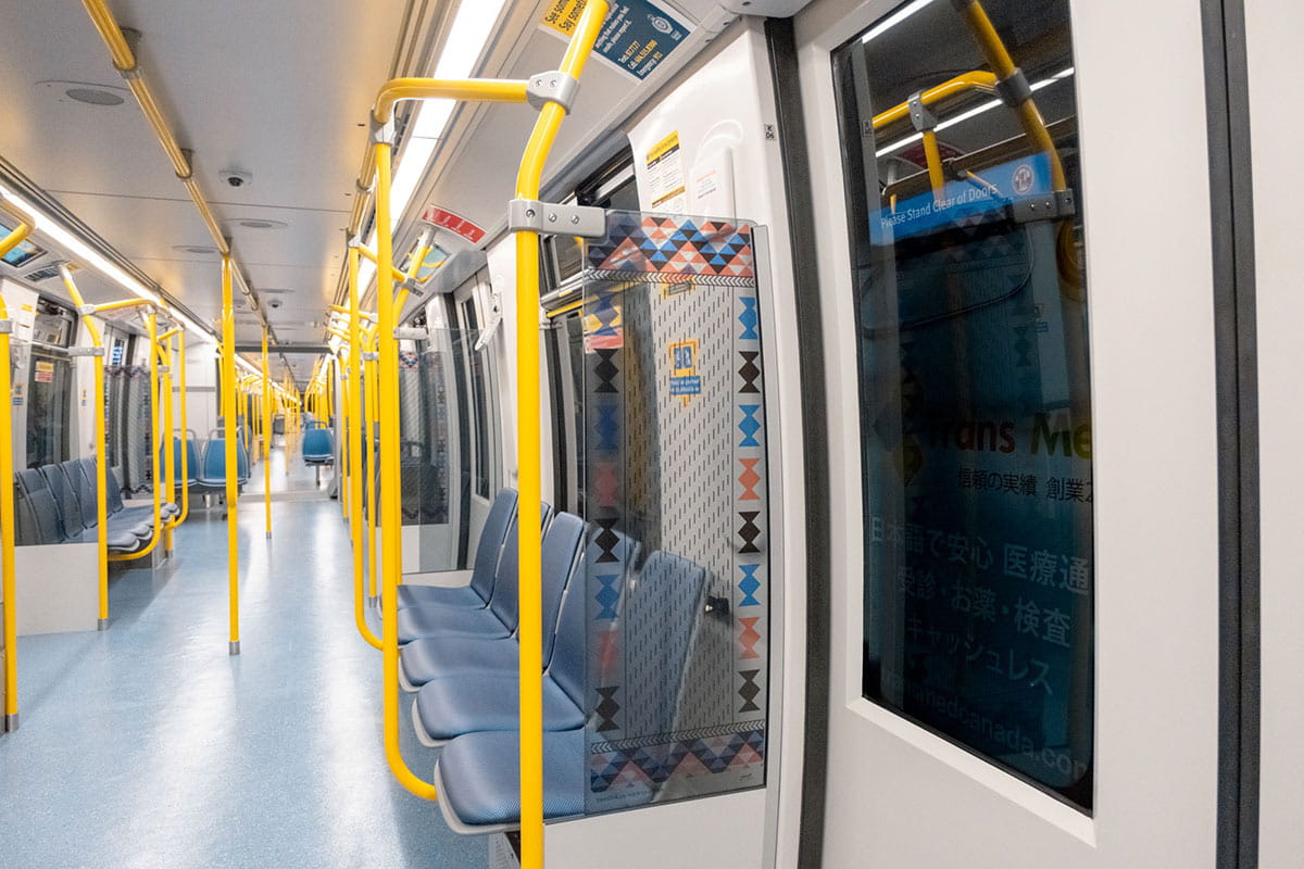Artwork showing stylized figures and paths in blue, red, and yellow tones on a Mark V SkyTrain car.