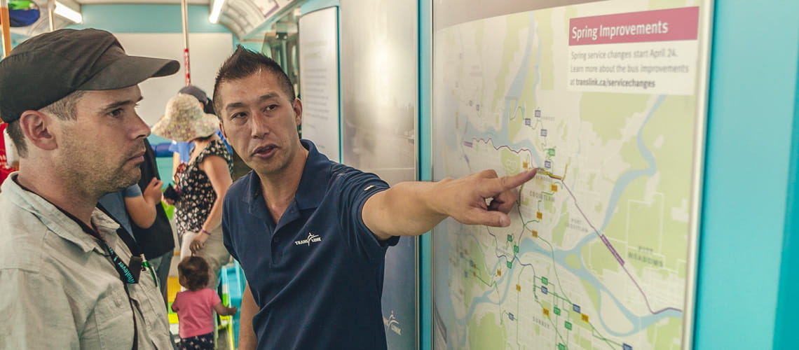 A male TransLink employee assisting a customer with a map