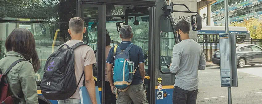 A group of post-secondary students wearing backpacks boarding the 99 bus
