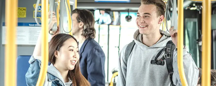 Two post-secondary aged students laughing while riding the bus