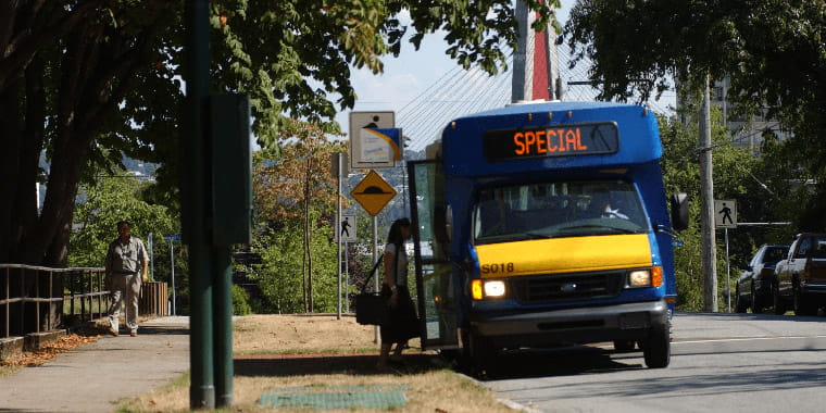 A shuttle bus parked at a bus stop on an empty street