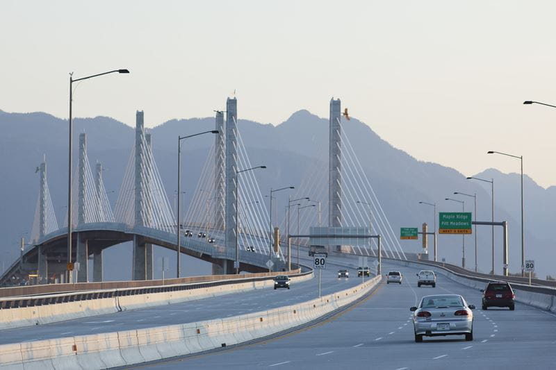 Cars driving down a bridge towards the mountains