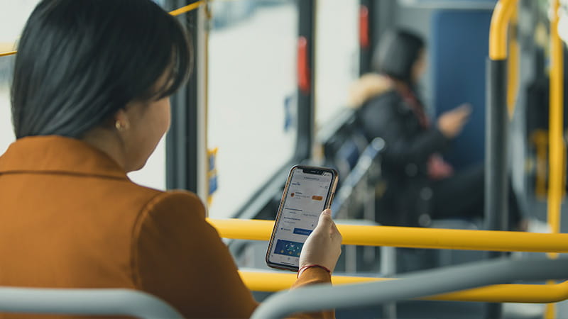 Passenger looking at alerts on phone while riding bus