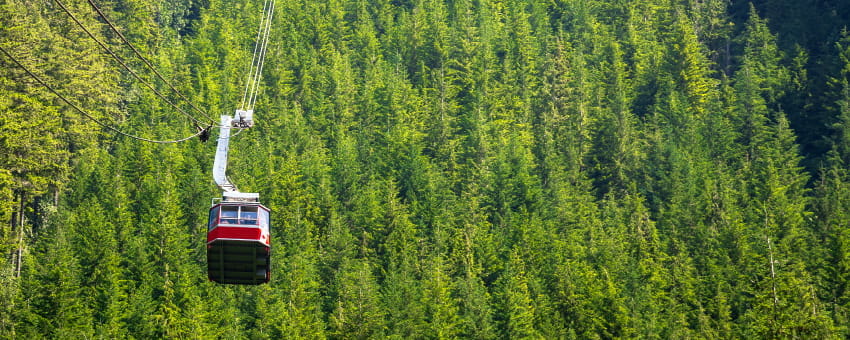 Grouse Mountain Gondola cable-car travelling up the mountain with trees in the background