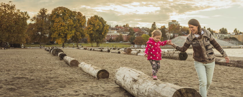 A mother and her child playing on the logs at Kits Beach