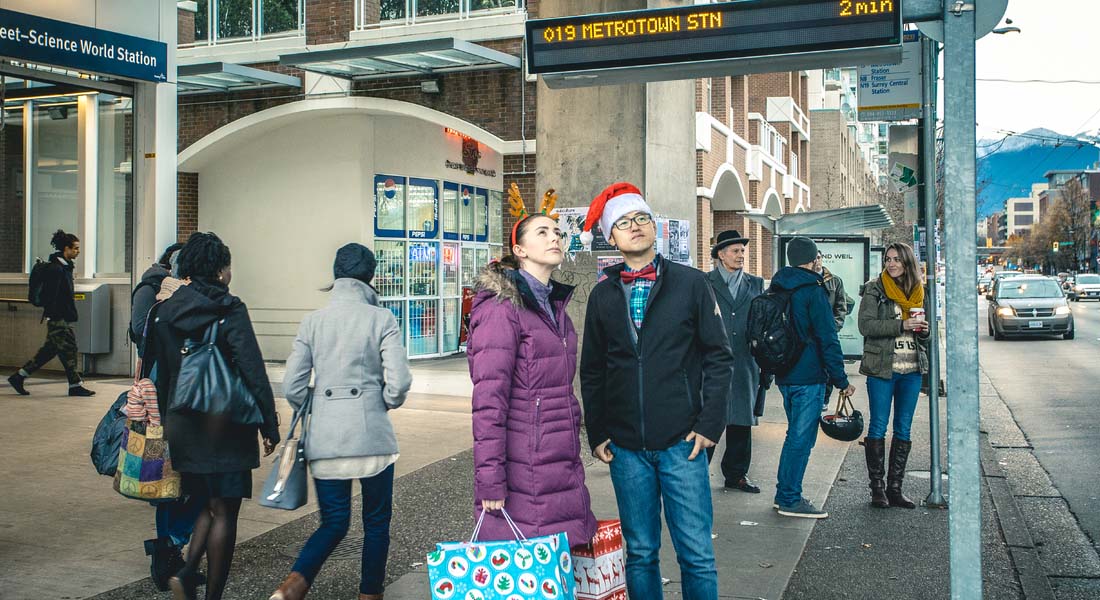 A couple with shopping bags waiting for the #9 bus at Main Street–Science World Station