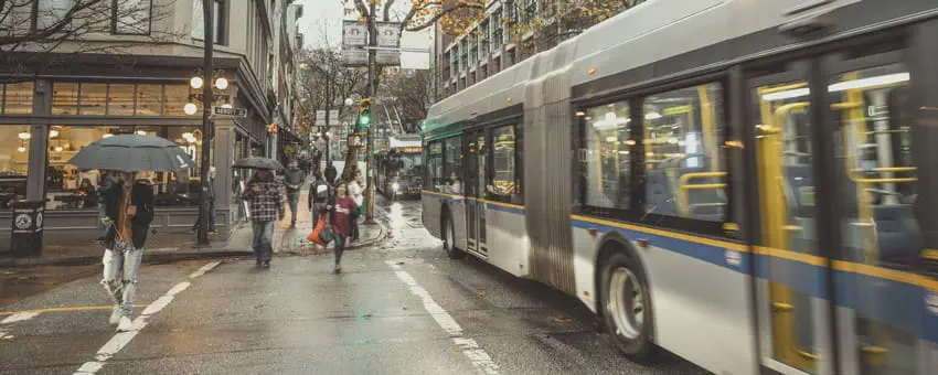 Bus travelling down Hastings street in rainy winter weather while pedestrians pass by